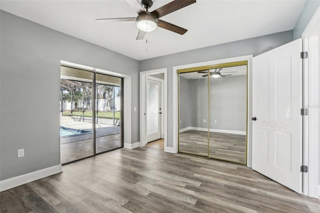 unfurnished bedroom with wood-type flooring, access to outside, and ceiling fan