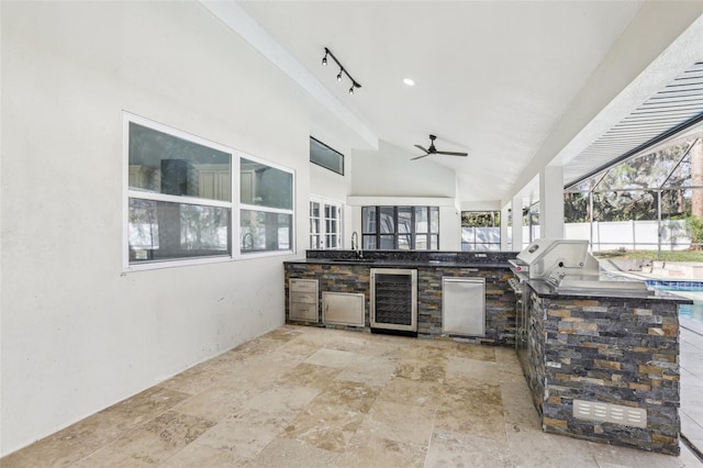 view of patio with sink, ceiling fan, glass enclosure, wine cooler, and an outdoor kitchen