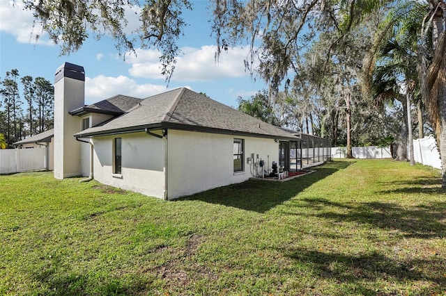 view of side of property with glass enclosure and a lawn