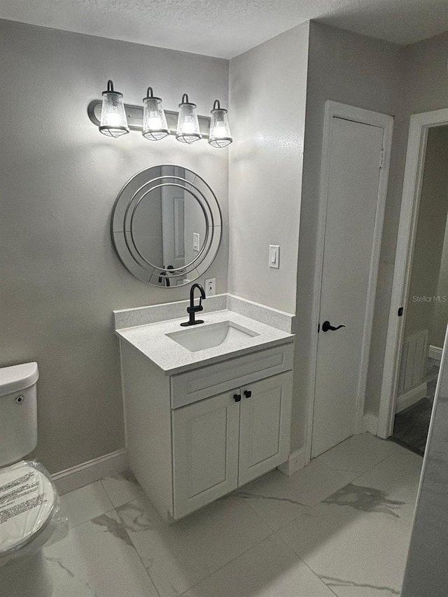 bathroom featuring vanity, a textured ceiling, and toilet