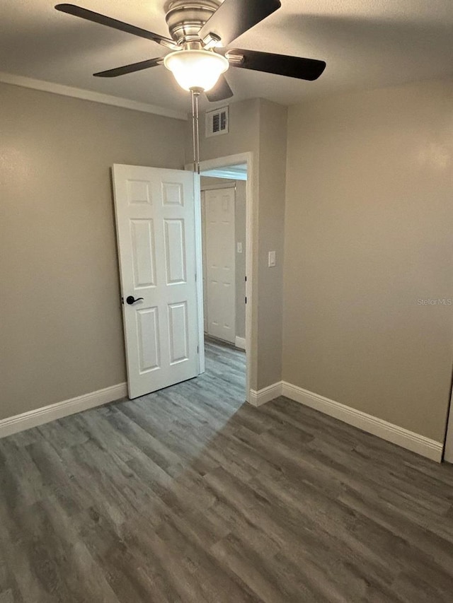 empty room with crown molding, ceiling fan, and dark hardwood / wood-style flooring