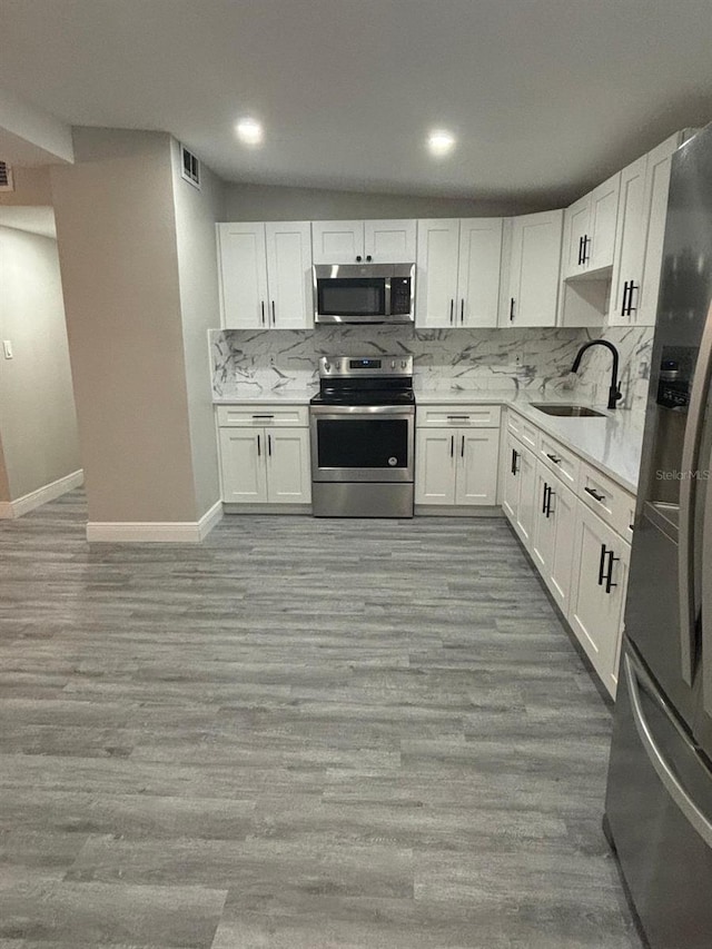 kitchen with white cabinetry, sink, light wood-type flooring, and appliances with stainless steel finishes