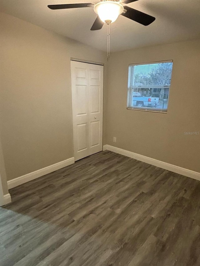 unfurnished bedroom with dark wood-type flooring, ceiling fan, and a closet