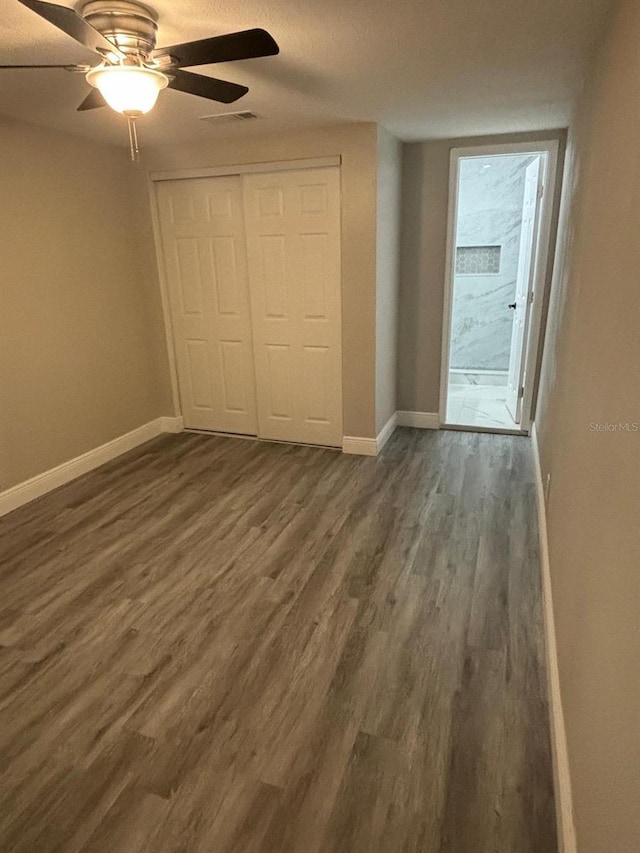 unfurnished bedroom with dark hardwood / wood-style flooring, a closet, and ceiling fan