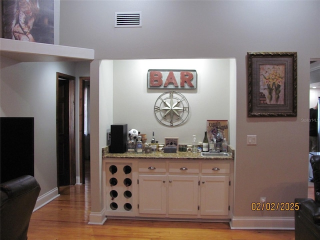 bar featuring light hardwood / wood-style flooring and stone countertops