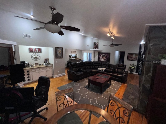 living room with hardwood / wood-style flooring, ceiling fan, and vaulted ceiling