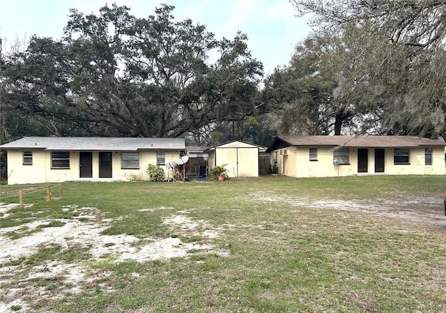 single story home with a shed, a front lawn, and an outbuilding