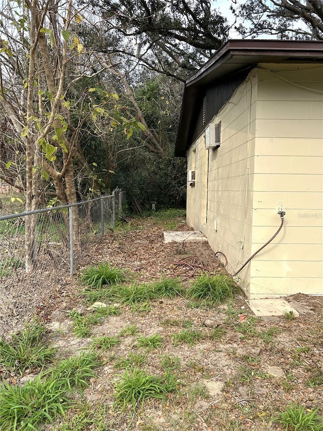 view of side of property with fence, concrete block siding, and an AC wall unit