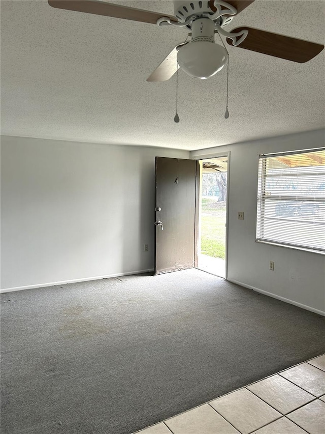 carpeted spare room featuring a textured ceiling, a ceiling fan, and baseboards