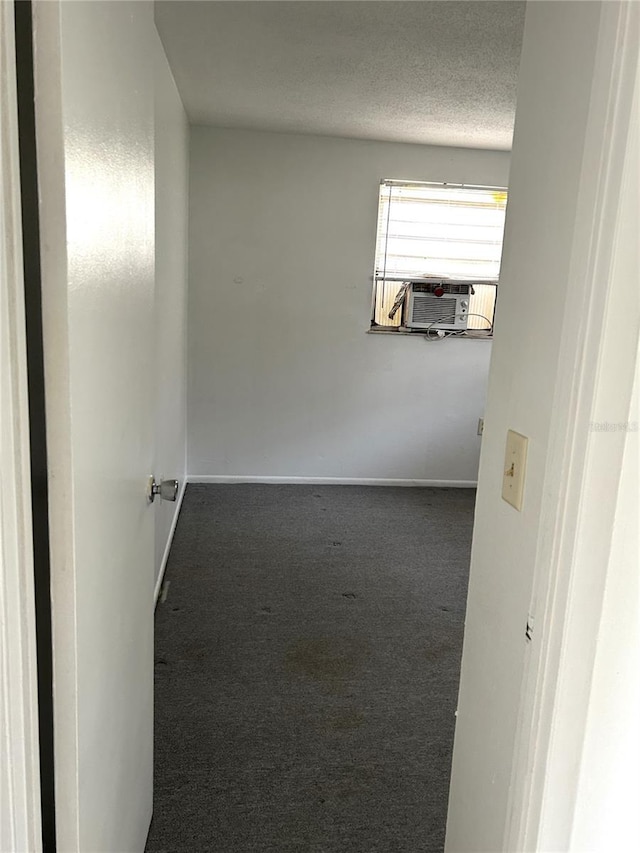 corridor featuring carpet, cooling unit, a textured ceiling, and baseboards