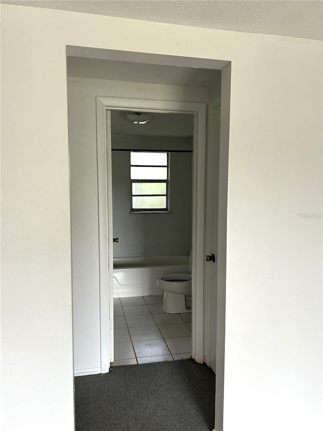 hall featuring a textured ceiling and tile patterned floors