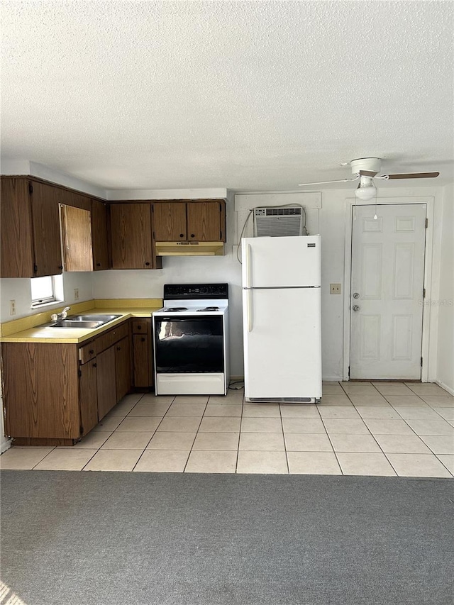 kitchen featuring white appliances, light tile patterned floors, light countertops, under cabinet range hood, and a sink