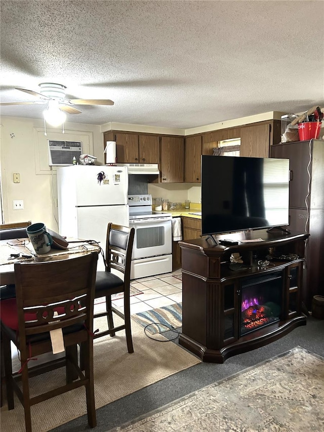 kitchen with white appliances, a wall mounted air conditioner, light countertops, a textured ceiling, and under cabinet range hood