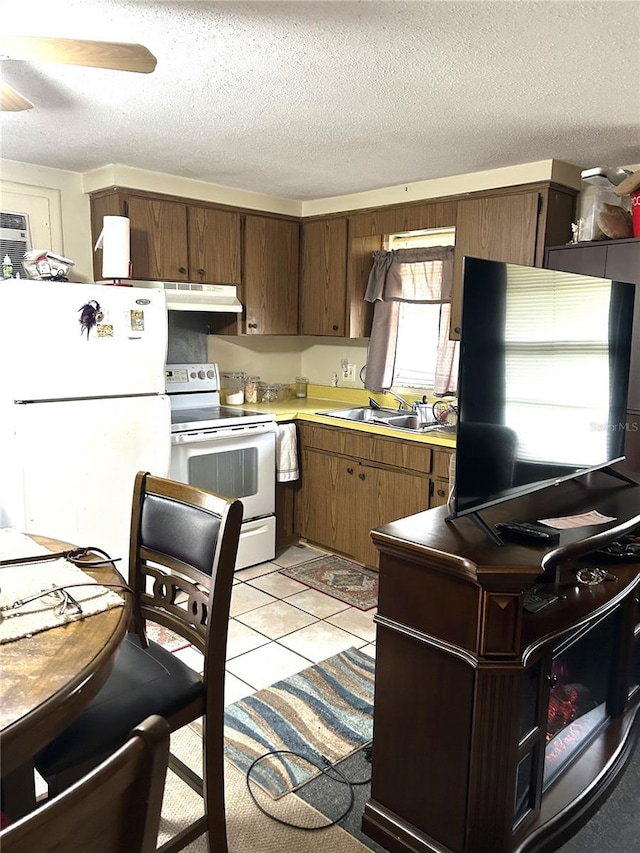 kitchen with light tile patterned floors, light countertops, a sink, white appliances, and under cabinet range hood