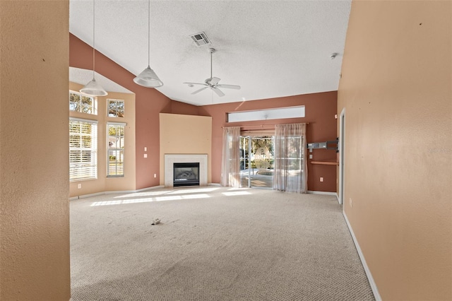 unfurnished living room with high vaulted ceiling, a fireplace, carpet floors, ceiling fan, and a textured ceiling