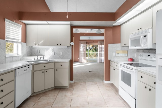 kitchen with white appliances, light tile patterned floors, sink, and white cabinets