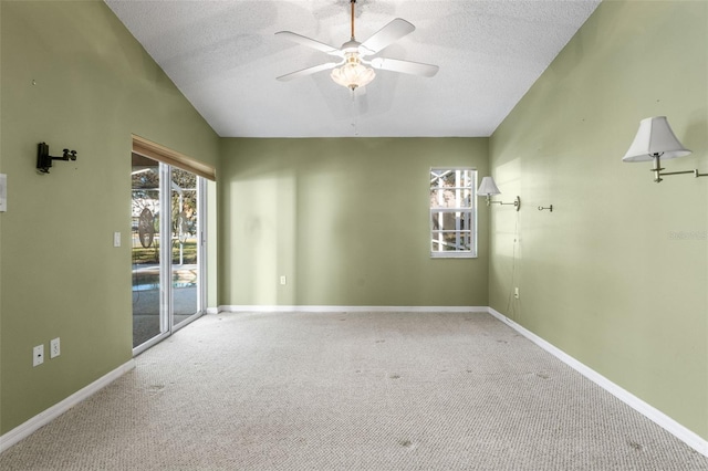 spare room featuring vaulted ceiling, ceiling fan, carpet, and a textured ceiling