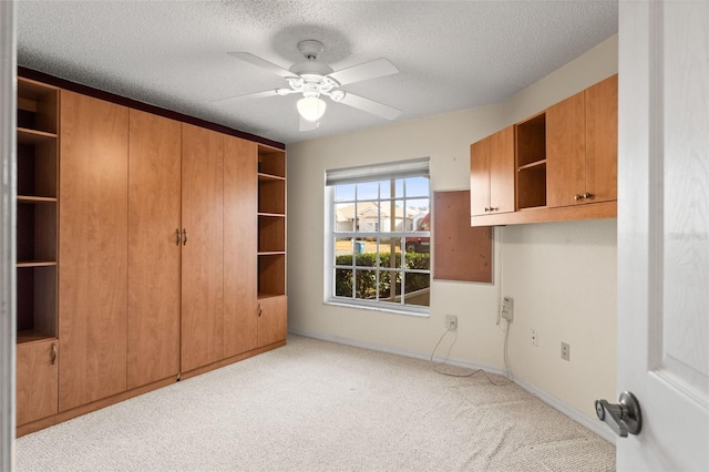 washroom with ceiling fan, light colored carpet, and a textured ceiling