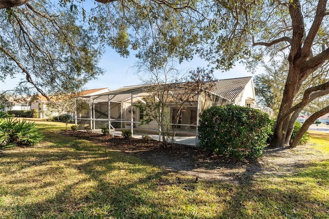 back of house with a lanai and a lawn