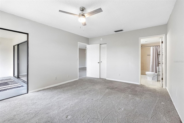 unfurnished bedroom featuring ceiling fan, connected bathroom, carpet floors, and a textured ceiling