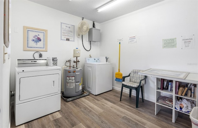 clothes washing area with independent washer and dryer, hardwood / wood-style flooring, water heater, and a textured ceiling