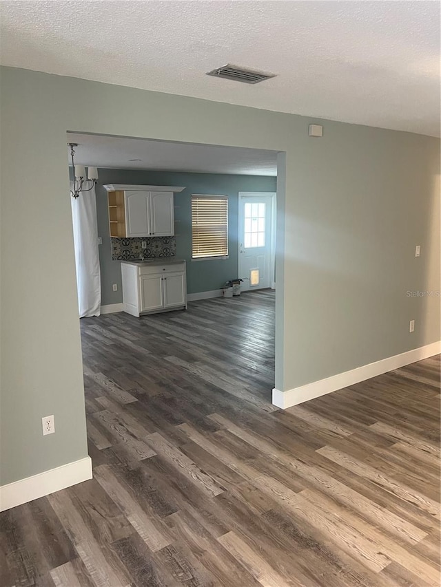 unfurnished living room with dark hardwood / wood-style flooring, sink, and a textured ceiling