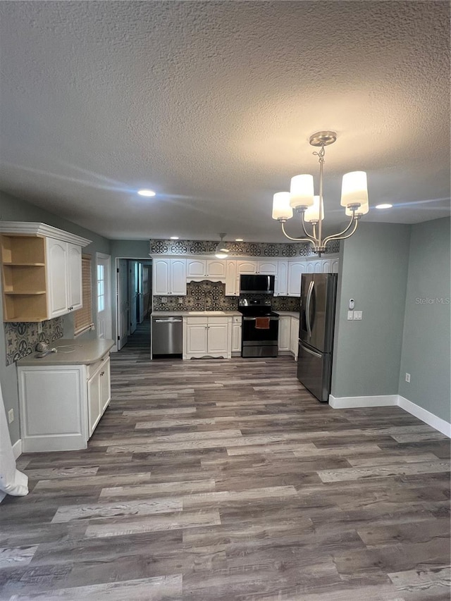 kitchen with appliances with stainless steel finishes, white cabinets, a chandelier, and decorative light fixtures