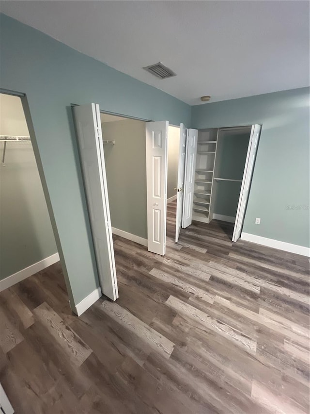 unfurnished bedroom with dark wood-type flooring and two closets