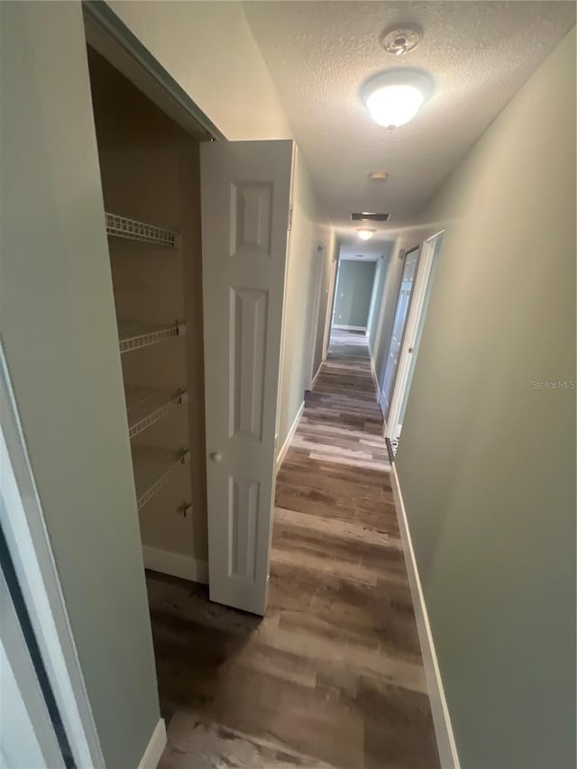 corridor with wood-type flooring and a textured ceiling