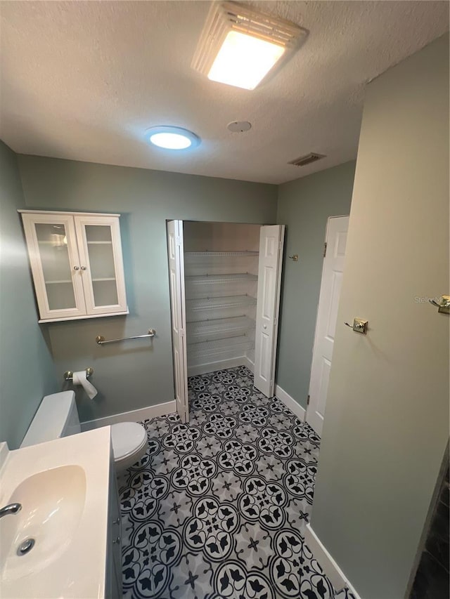 bathroom with toilet, tile patterned flooring, sink, and a textured ceiling