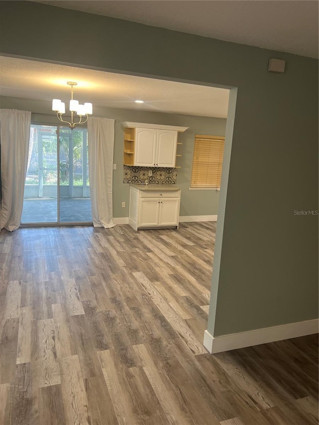 unfurnished living room with a chandelier and light wood-type flooring