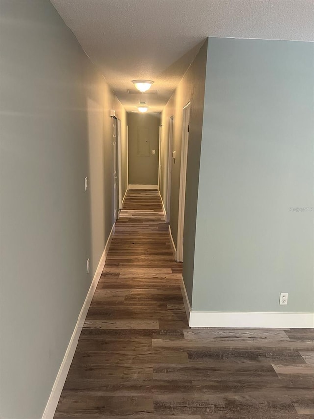 hallway featuring dark hardwood / wood-style flooring and a textured ceiling