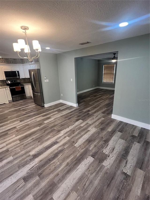 unfurnished living room with ceiling fan with notable chandelier, a textured ceiling, and dark hardwood / wood-style flooring