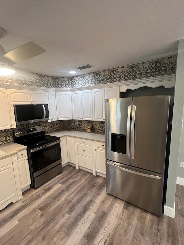 kitchen featuring dark wood-type flooring, stainless steel appliances, decorative backsplash, and white cabinets