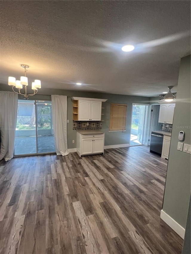 unfurnished living room featuring dark wood-type flooring, plenty of natural light, a textured ceiling, and a notable chandelier