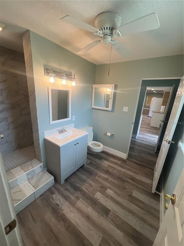 bathroom featuring tiled shower, a textured ceiling, vanity, ceiling fan, and hardwood / wood-style floors