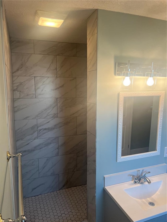 bathroom with vanity, a textured ceiling, and a tile shower