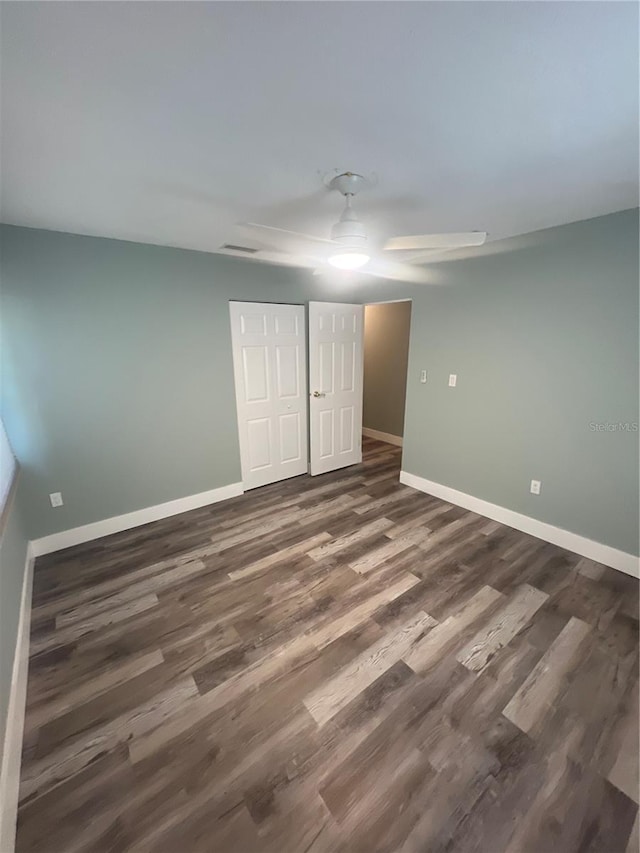 unfurnished bedroom with dark hardwood / wood-style flooring, a closet, and ceiling fan