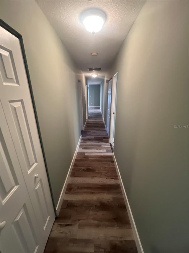 hall with dark wood-type flooring and a textured ceiling