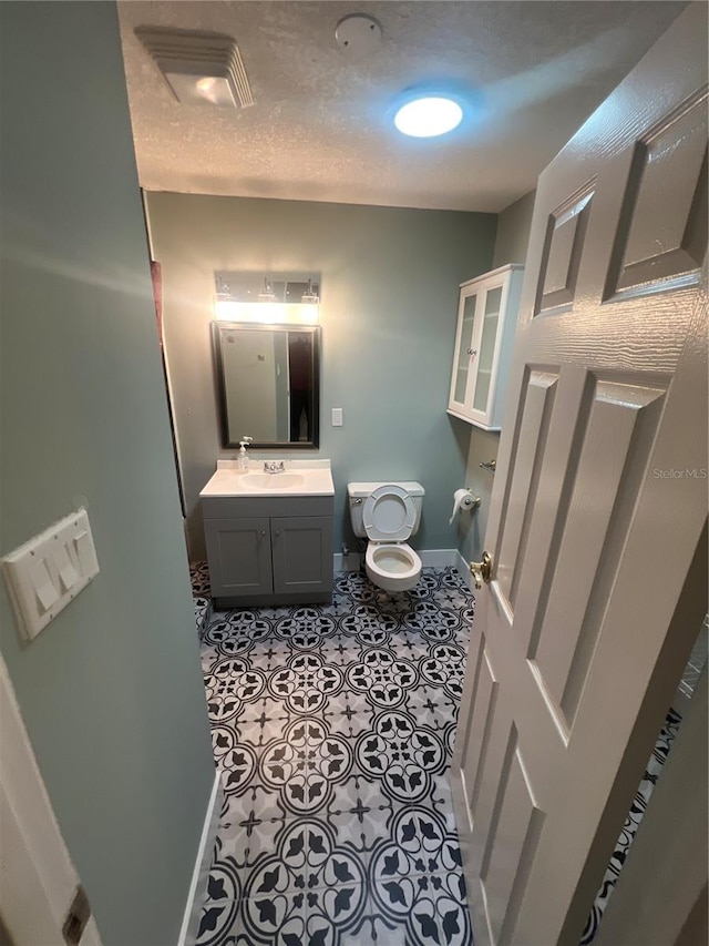 bathroom with tile patterned flooring, vanity, a textured ceiling, and toilet