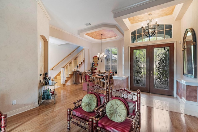 foyer entrance with an inviting chandelier, light hardwood / wood-style floors, and french doors