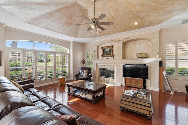 living room with crown molding, dark wood-type flooring, a fireplace, and ceiling fan