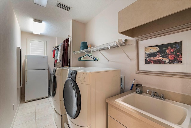 laundry area featuring independent washer and dryer, sink, a textured ceiling, and light tile patterned floors