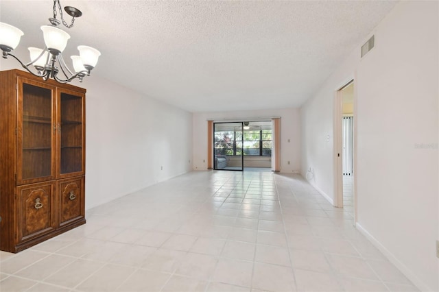 unfurnished room with light tile patterned floors, a textured ceiling, and a chandelier