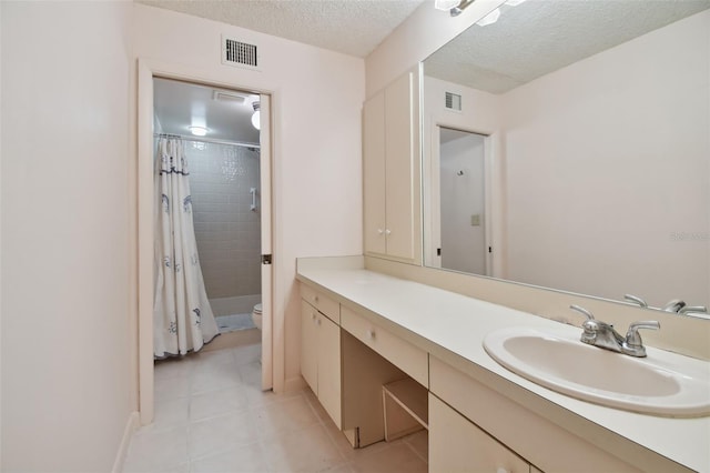 bathroom featuring tile patterned flooring, vanity, walk in shower, toilet, and a textured ceiling