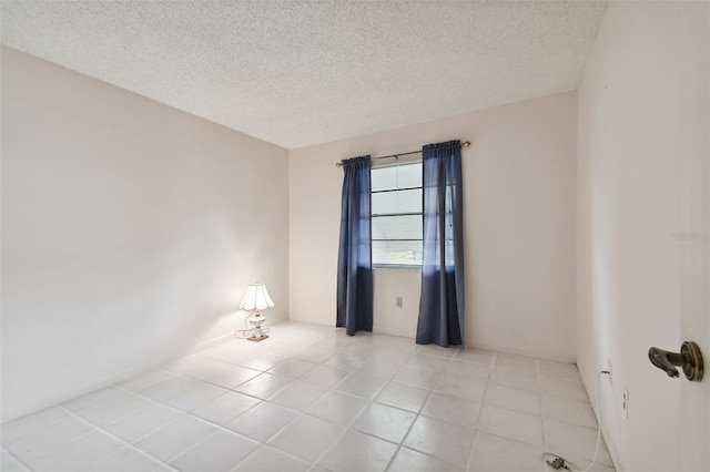 empty room with light tile patterned floors and a textured ceiling