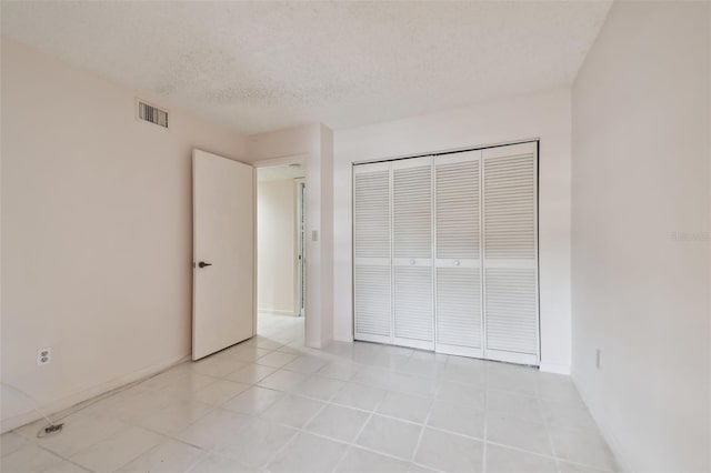 unfurnished bedroom featuring light tile patterned floors, a textured ceiling, and a closet