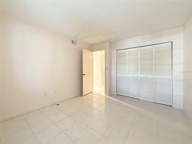 1601 43rd St N Unit 133, Saint Petersburg, FL 33713 - unfurnished bedroom with light tile patterned floors, visible vents, a textured ceiling, and a closet