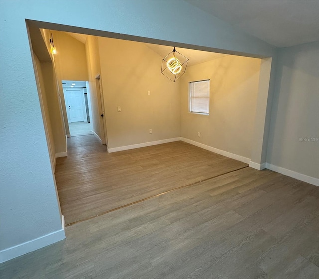 unfurnished room with hardwood / wood-style flooring and vaulted ceiling