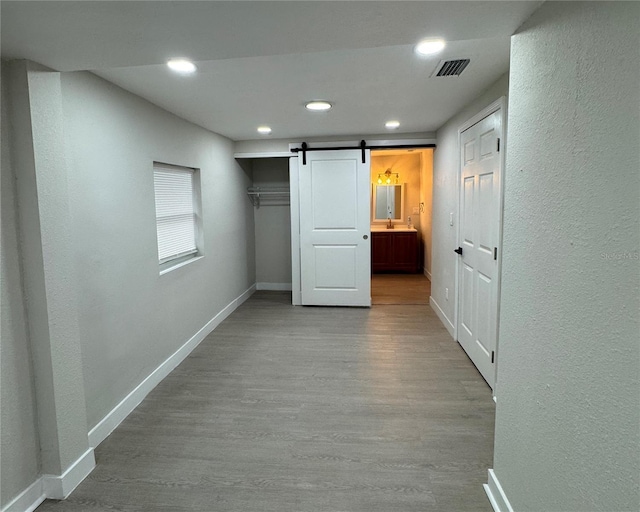 hallway with light hardwood / wood-style flooring and a barn door